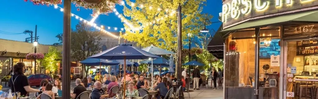 Outdoor restaurant tables under umbrellas and string lights.
